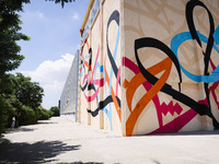 A moment of the press presentation of the mural Waves Only Exist Because the Wind Blows by eL Seed on the exterior walls of Pirelli HangarBi...