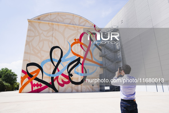 A moment of the press presentation of the mural Waves Only Exist Because the Wind Blows by eL Seed on the exterior walls of Pirelli HangarBi...