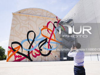 A moment of the press presentation of the mural Waves Only Exist Because the Wind Blows by eL Seed on the exterior walls of Pirelli HangarBi...