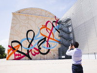 A moment of the press presentation of the mural Waves Only Exist Because the Wind Blows by eL Seed on the exterior walls of Pirelli HangarBi...