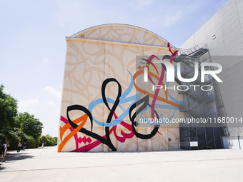 A moment of the press presentation of the mural Waves Only Exist Because the Wind Blows by eL Seed on the exterior walls of Pirelli HangarBi...