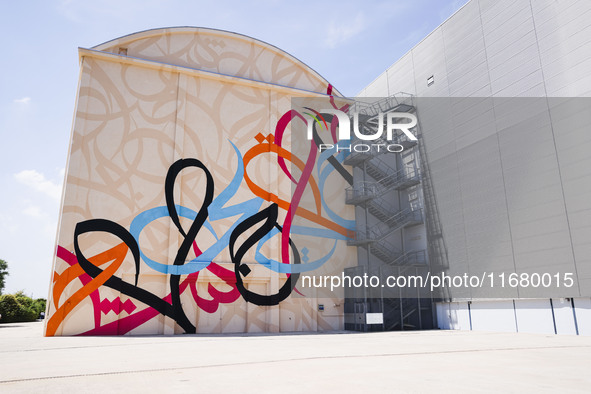 A moment of the press presentation of the mural Waves Only Exist Because the Wind Blows by eL Seed on the exterior walls of Pirelli HangarBi...