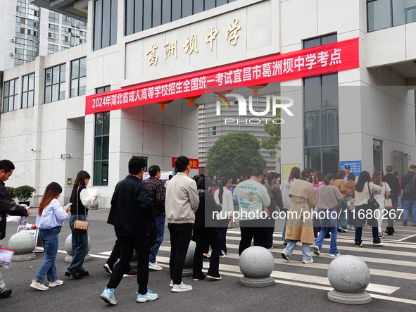 Candidates queue to enter the exam room during the 2024 National Adult College Entrance Examination in Yichang, Hubei province, China, on Oc...