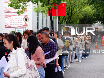 Candidates queue to enter the exam room during the 2024 National Adult College Entrance Examination in Yichang, Hubei province, China, on Oc...