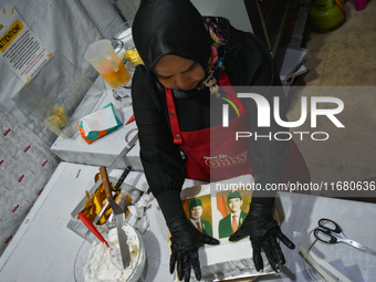 A pastry cook makes a tart with pictures of Indonesia's new president Prabowo Subianto and vice president Gibran Rakabuming Raka for the spe...