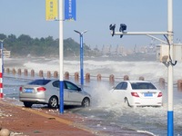 Cars pass a road covered with seawater at the seaside in Yantai, China, on October 19, 2024. (