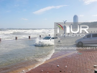 Cars pass a road covered with seawater at the seaside in Yantai, China, on October 19, 2024. (