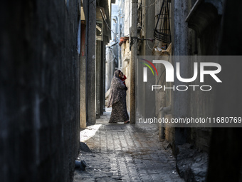 A Palestinian woman carrying a child walks through the Maghazi camp for Palestinian refugees in the central Gaza Strip on October 19, 2024,...