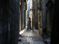 A Palestinian woman carrying a child walks through the Maghazi camp for Palestinian refugees in the central Gaza Strip on October 19, 2024,...