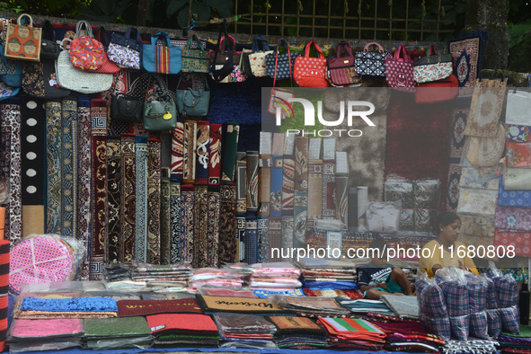 A child plays with a mobile while his parents sell household items on display at a roadside stall in Siliguri, India, on October 19, 2024. I...