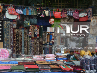 A child plays with a mobile while his parents sell household items on display at a roadside stall in Siliguri, India, on October 19, 2024. I...