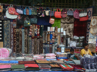 A child plays with a mobile while his parents sell household items on display at a roadside stall in Siliguri, India, on October 19, 2024. I...