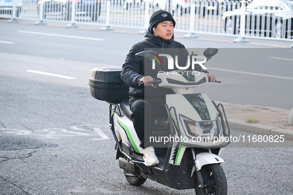 A citizen rides in thick clothes as temperatures plummet in Beijing, China, on October 19, 2024. 