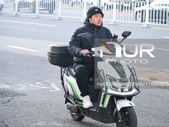 A citizen rides in thick clothes as temperatures plummet in Beijing, China, on October 19, 2024. (