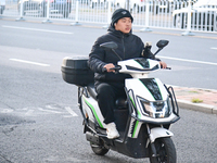 A citizen rides in thick clothes as temperatures plummet in Beijing, China, on October 19, 2024. (