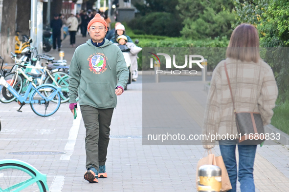 Citizens walk in thick clothes as temperatures plummet in Beijing, China, on October 19, 2024. 