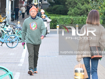 Citizens walk in thick clothes as temperatures plummet in Beijing, China, on October 19, 2024. (