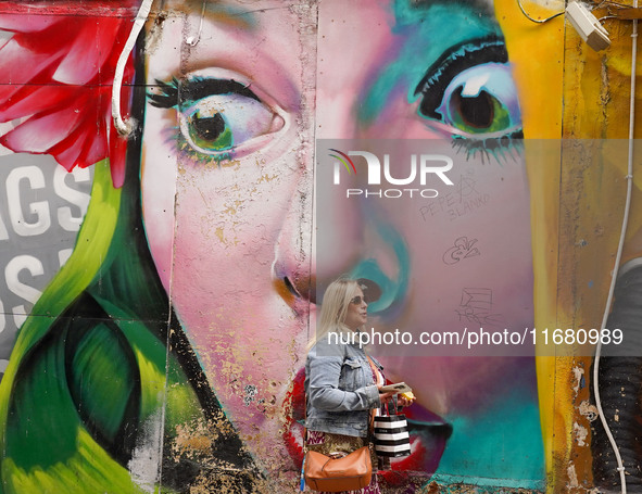 A woman walks past graffiti in Athens, Greece, on October 19, 2024. 