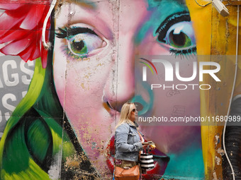 A woman walks past graffiti in Athens, Greece, on October 19, 2024. (