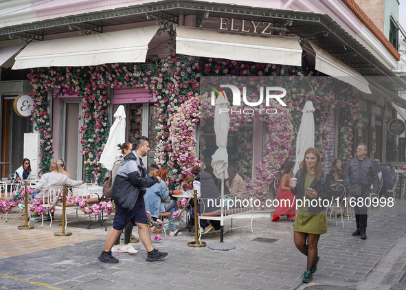 People walk past a coffee shop in Athens, Greece, on October 19, 2024. 