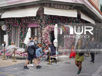 People walk past a coffee shop in Athens, Greece, on October 19, 2024. (