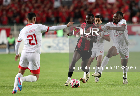 Tagnouo Mbe Jacques Amour of CR Belouizdad (R) competes for the ball with Likonza Adango Glody (C) of USM Alger during the football match be...