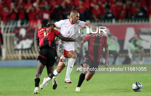 Islam Slimani of CR Belouizdad (C) competes for the ball with Likonza Adango Glody (L) of USM Alger during the football match between CR Bel...