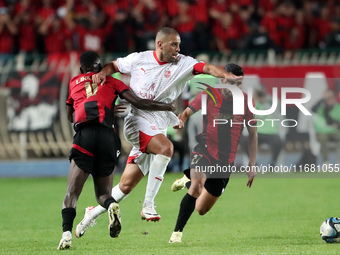 Islam Slimani of CR Belouizdad (C) competes for the ball with Likonza Adango Glody (L) of USM Alger during the football match between CR Bel...