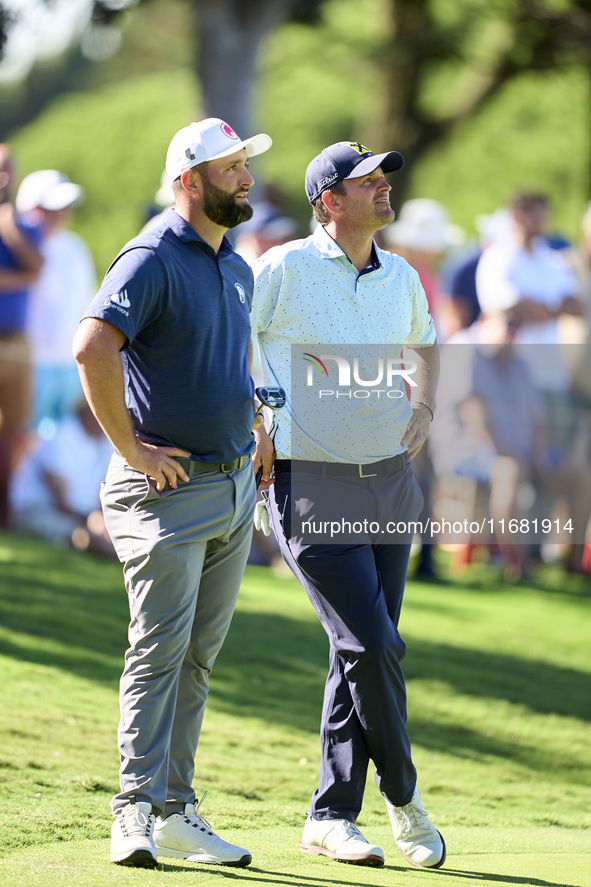 In San Roque, Spain, on October 19, 2024, Jon Rahm of Spain talks with Bernd Wiesberger of Austria on the 14th green on the third day of the...