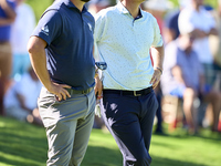 In San Roque, Spain, on October 19, 2024, Jon Rahm of Spain talks with Bernd Wiesberger of Austria on the 14th green on the third day of the...