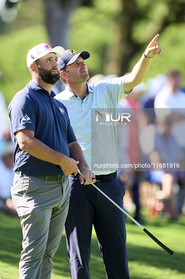 In San Roque, Spain, on October 19, 2024, Jon Rahm of Spain talks with Bernd Wiesberger of Austria on the 14th green on the third day of the...