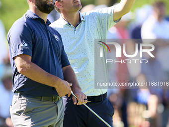 In San Roque, Spain, on October 19, 2024, Jon Rahm of Spain talks with Bernd Wiesberger of Austria on the 14th green on the third day of the...