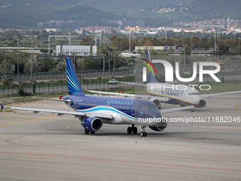 An Airbus A319-111 from Azerbaijan Airlines and a Boeing 737-8AS from Ryanair prepare for takeoff on the runway at Barcelona Airport in Barc...