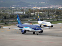 An Airbus A319-111 from Azerbaijan Airlines and a Boeing 737-8AS from Ryanair prepare for takeoff on the runway at Barcelona Airport in Barc...