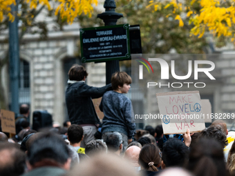 A demonstrator holds a sign reading ''make love not war'' during a gathering at the Place de La Republique in Paris, France, on October 19,...