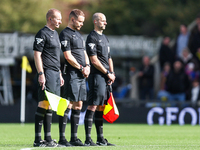 Assistant referee Matthew McGrath, referee Leigh Doughty, and assistant referee Nigel Lugg observe a minute's silence as they pay their resp...