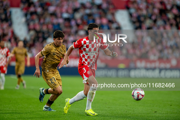 In Girona, Spain, on October 19, 2024, Jon Mikel Aramburu of Real Sociedad and Miguel Gutierrez of Girona FC compete for the ball during the...