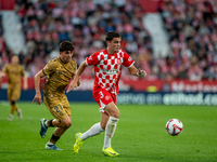 In Girona, Spain, on October 19, 2024, Jon Mikel Aramburu of Real Sociedad and Miguel Gutierrez of Girona FC compete for the ball during the...