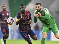 Almoez Abdulla (L) of Al Duhail FC battles for the ball with Driss Fettouhi of Al Ahli SC during the Ooredoo Qatar Stars League 24/25 match...