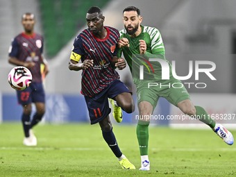 Almoez Abdulla (L) of Al Duhail FC battles for the ball with Driss Fettouhi of Al Ahli SC during the Ooredoo Qatar Stars League 24/25 match...