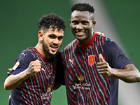 Michael Olunga (R) of Al Duhail FC celebrates with his teammate after scoring a goal during the Ooredoo Qatar Stars League 24/25 match betwe...