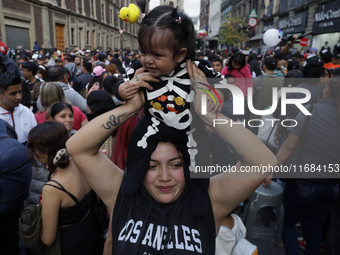 A woman carries her baby during the Zombie March in Mexico City, Mexico, on October 19, 2024, which starts from the Monument to the Revoluti...