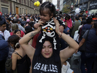 A woman carries her baby during the Zombie March in Mexico City, Mexico, on October 19, 2024, which starts from the Monument to the Revoluti...