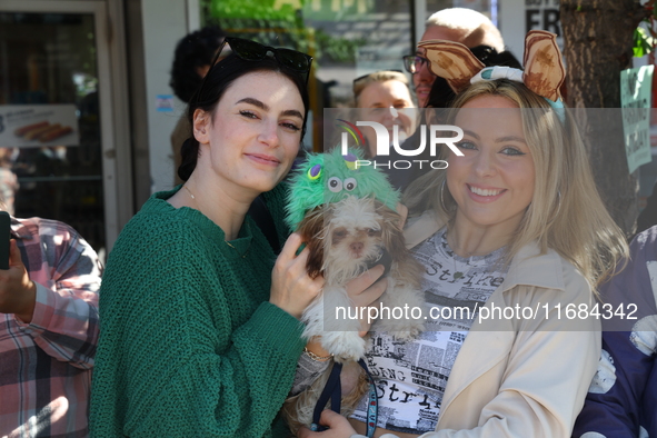 A dog is held up by two women watching the 34th Annual Tompkins Square Halloween Dog Parade in Tompkins Square Park in New York City, USA, o...