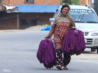 A woman carries globe amaranth (Makhamali) flower garlands ready to sell in the market for the Tihar festival celebration in Bhaktapur, Nepa...