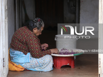 A Nepalese woman weaves globe amaranth (Makhamali) flowers to make garlands to sell in the market for the Tihar festival celebration in Bhak...