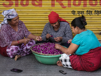 Nepalese women weave globe amaranth (Makhamali) flowers to make garlands to sell in the market for the Tihar festival celebration in Bhaktap...