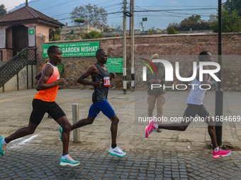 An Indian policeman stands guard as participants run during the Kashmir Marathon on the banks of Dal Lake in Srinagar, Jammu and Kashmir, on...