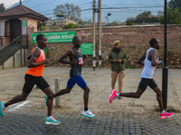 An Indian policeman stands guard as participants run during the Kashmir Marathon on the banks of Dal Lake in Srinagar, Jammu and Kashmir, on...