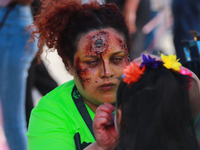 A woman applies makeup to a person during the annual Zombie Walk 2024 Mx, from the Monument to the Revolution to the main square Zocalo in M...